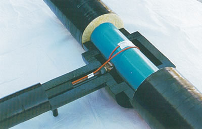 Robinet de prise en charge branché directement sur un collecteur d'eau principal en PVC préisolé. Le tuyau de branchement de 25 mm. (1 po.) en cuivre recuit de type K installé dans un conduit en PEHD préisolé de 50 mm (2 po;). Le câble de traçage THERMOÇÂBLE® est collé au tuyau de cuivre et fait un tour complet autour du collecteur en PVC.