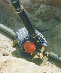 Électricien en train de tirer un câble de traçage électrique THERMOCÂBLE® à faible puissance sur un tuyau de branchement de 25 mm (1 po.) avec robinet de branchement, dans le Nord de l'Ontario.